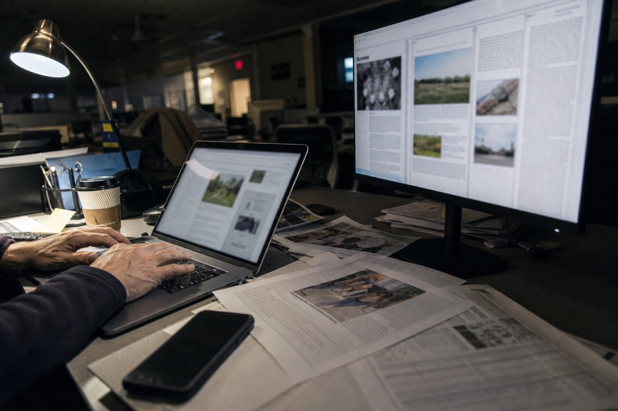 Hands at a newsroom desk at night, building a newspaper’s site.