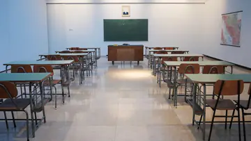 Empty classroom with rows of desks facing a chalkboard